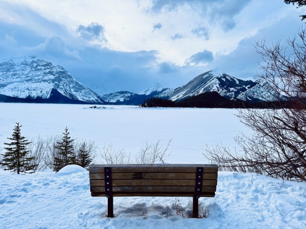 A scenic spot bench at the heavily snow-covered Upper Kananaskis Lake shoreline