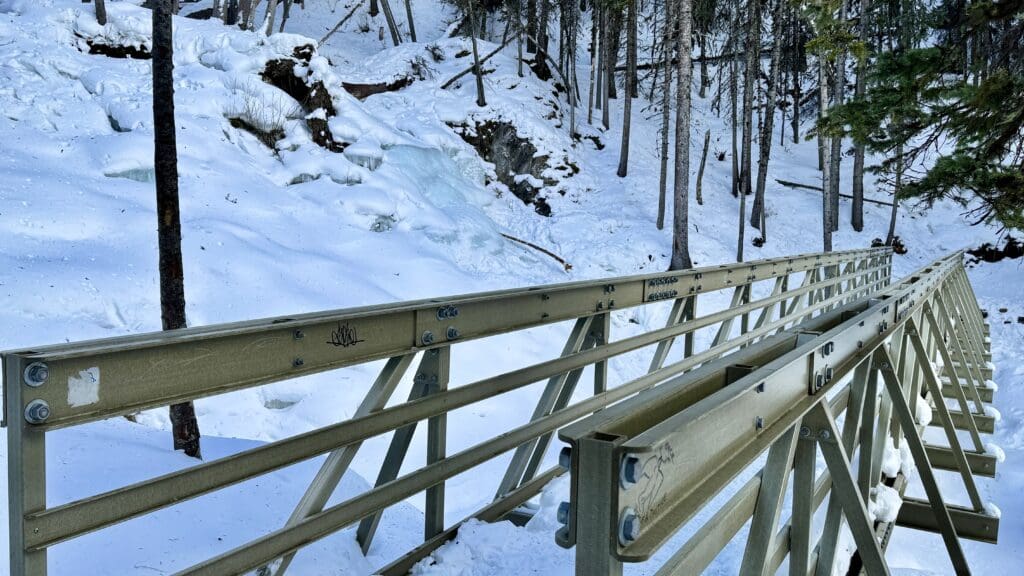 A short but steady bridge across Upper Kananaskis Trail next to a frozen fall