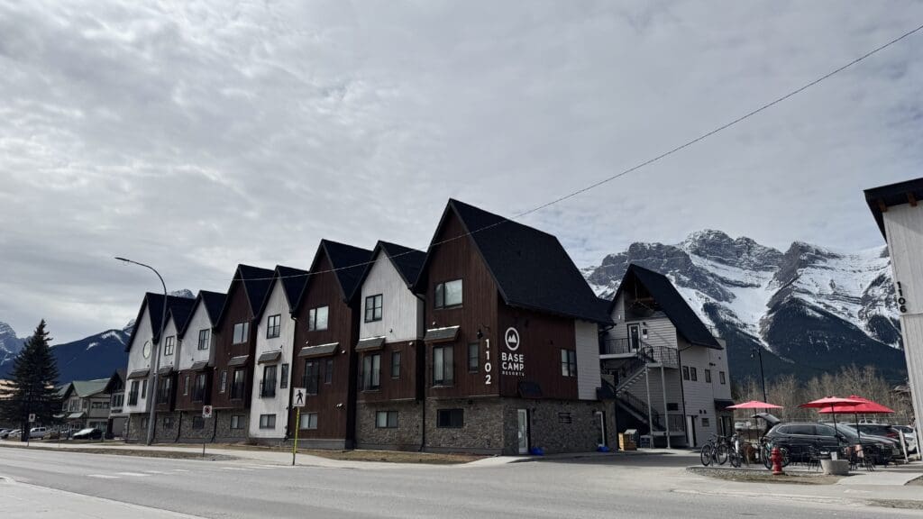 Exterior view of Basecamp Lodge Canmore with rustic alpine-style architecture, nestled beneath the Rocky Mountains in downtown Canmore