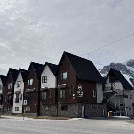 Exterior view of Basecamp Lodge Canmore with rustic alpine-style architecture, nestled beneath the Rocky Mountains in downtown Canmore