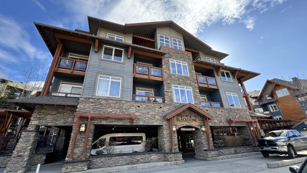 Blackstone Mountain Lodge by Clique in Canmore, Alberta featuring rustic stone and timber architecture with luxury mountain lodge appeal under a clear sky