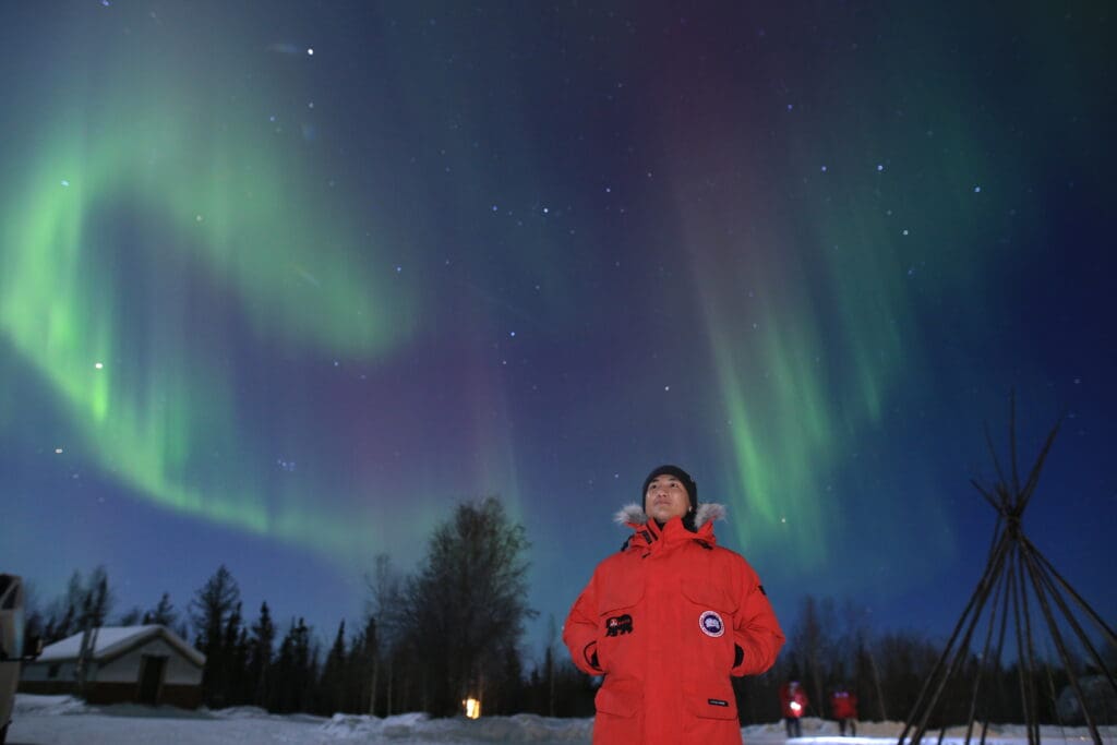 Evan wearing multiple layers with amazing aurora in Yellowknife when resting in the lounge of Yellowknife aurora tour