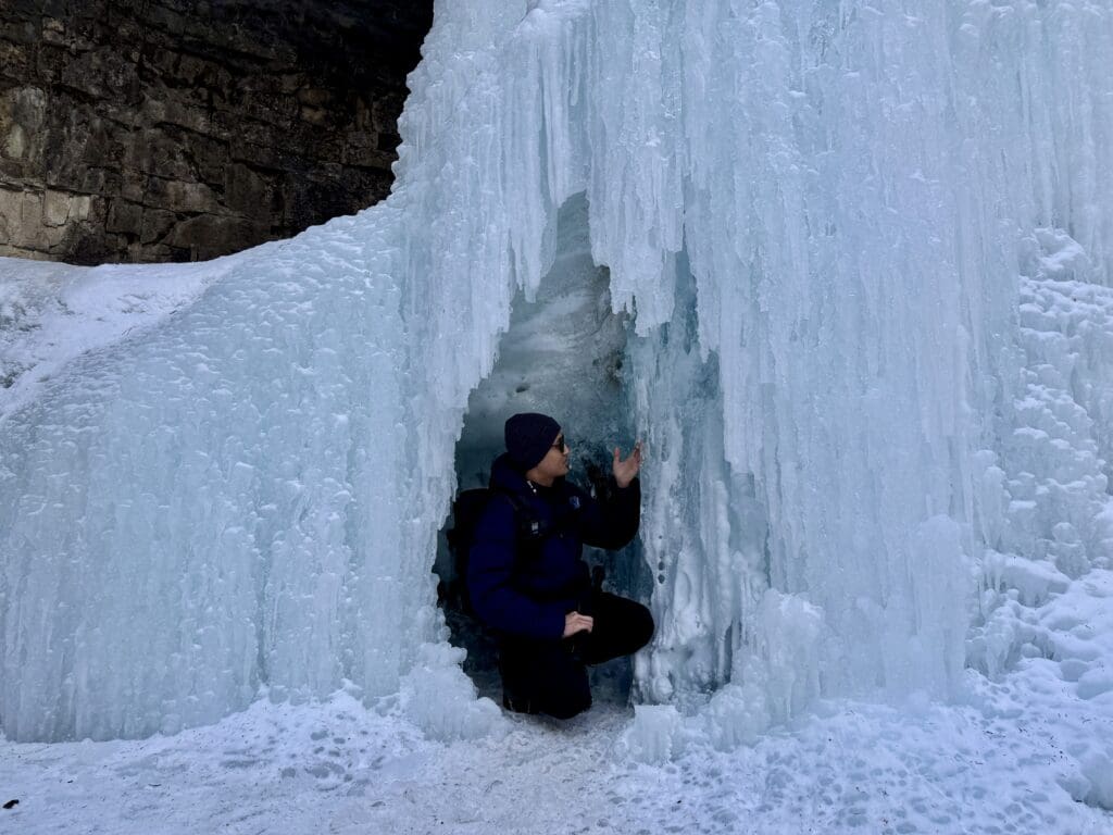 A tiny cave that fits a person under the frozen Marmot Falls in Kananaskis