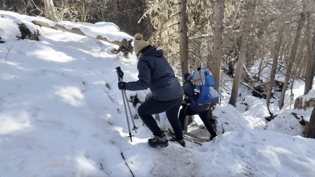 A family carefully walking down a short stairs to Upper Falls Kananaskis with packed snow and in icy condition