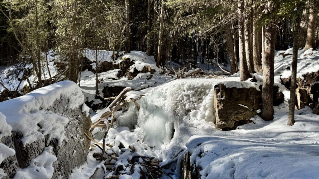 A small frozen falls with big rocks on it along the way to Upper Falls Kananaskis