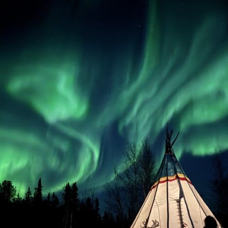 Spectacular aurora on the lounge of our aurora tour with a decorative indigenous camp in Yellowknife