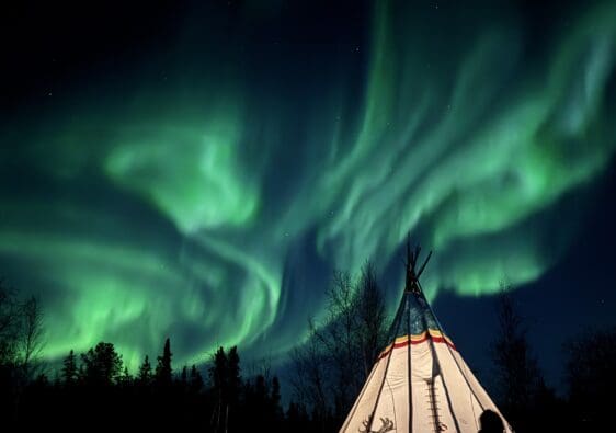 Spectacular aurora on the lounge of our aurora tour with a decorative indigenous camp in Yellowknife