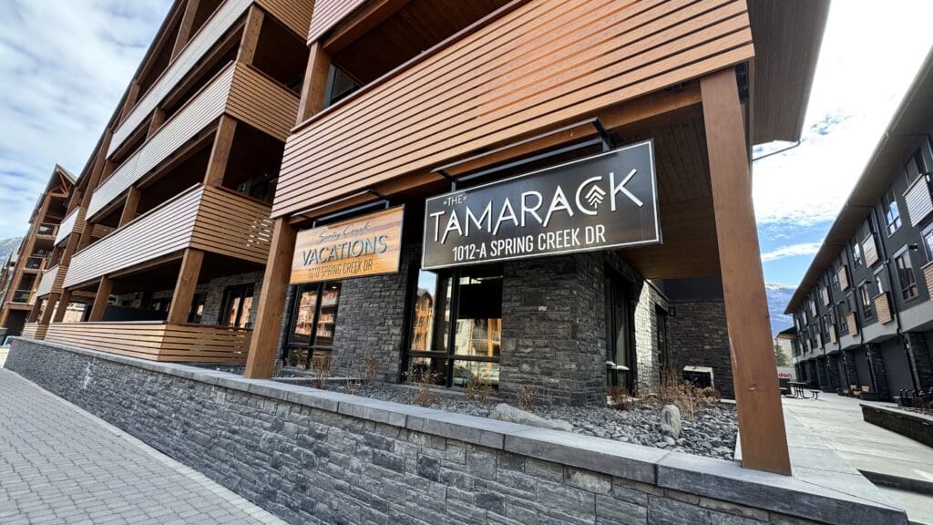 Exterior view of The Tamarack building at Spring Creek Vacations in Canmore, Alberta, showcasing modern wood and stone architecture near the Canadian Rockies