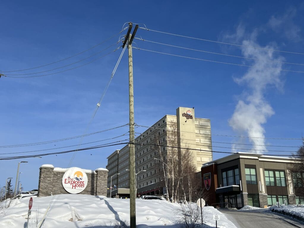 A big hotel in Yellowknife with a parking lot and a restaurant next to it