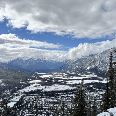 View of Banff Town after hiking up the Tunnel Mountain in Banff National Park with lots of snow-covered Rocky Mountains at the back