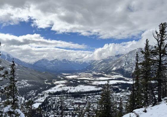 View of Banff Town after hiking up the Tunnel Mountain in Banff National Park with lots of snow-covered Rocky Mountains at the back