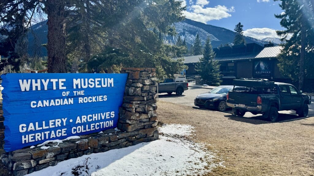 The wooden sign of Whyte Museum of the Canadian Rockies in Banff and the museum at the back