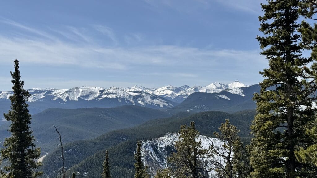The view of panoramic mountain vista with snow-capped peaks and evergreen forests along Prairie Mountain Trail in Kananaskis